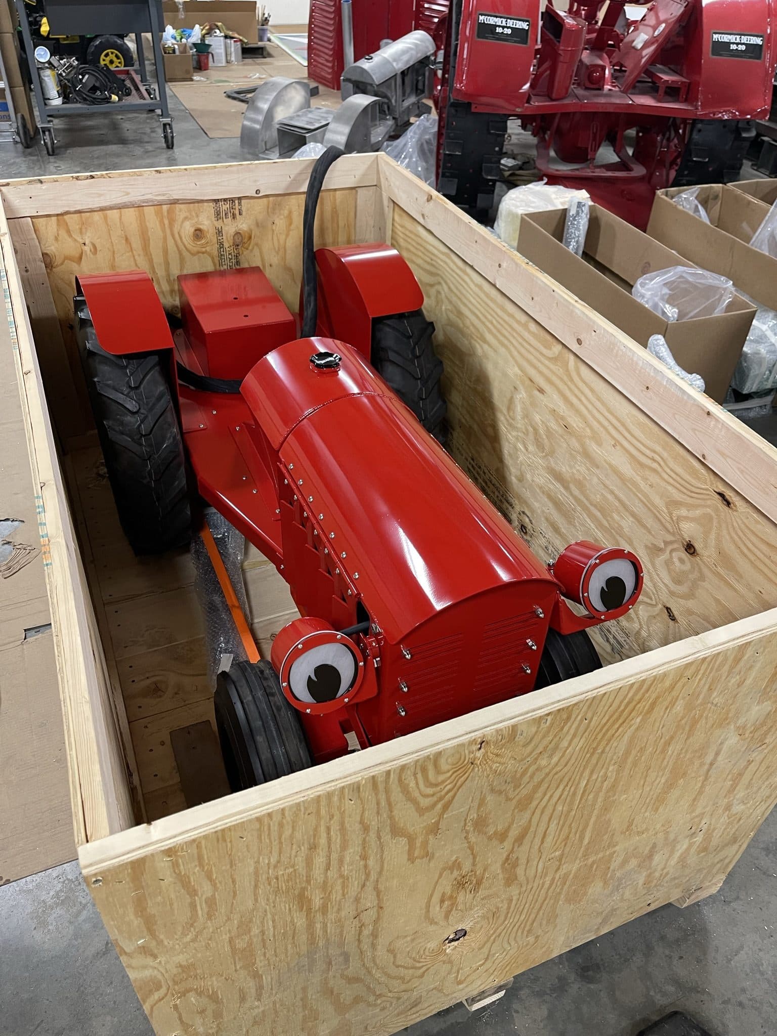 A red Zack the Tractor packed in a wooden shipping crate, ready to ship